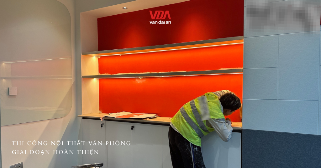 Thợ thi công xử lý mép vách ốp tường trang trí màu đỏ trong văn phòng.